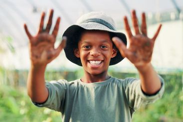 Portrait, dirty hands and black child in garden, palms...