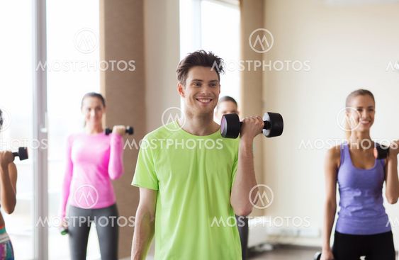 group of smiling people working out with dumbbells