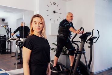 Personal female trainer with her client in ems suit in gym.