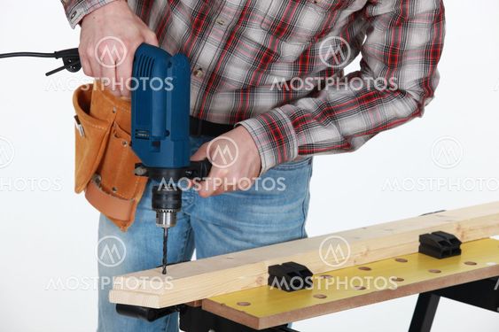 Carpenter drilling into wooden plank