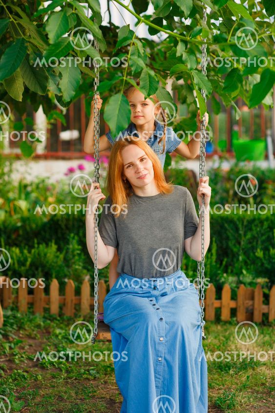 mom and daughter on swing in garden