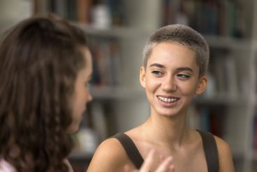 Beautiful teenage girl hipster listen to female mate...