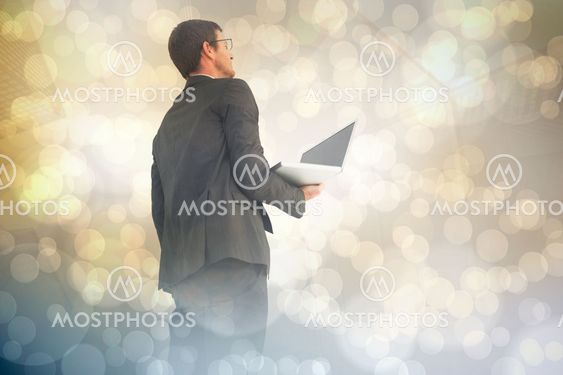 Composite image of businessman looking up holding laptop
