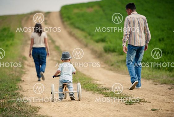 Family with little boy on tricycle in nature