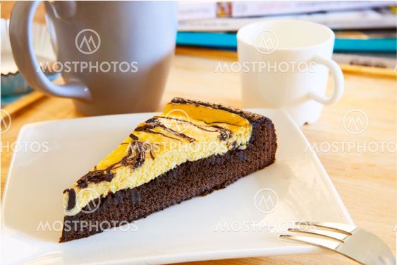browny cheese cake on white dish with coffee cup and relaxing magazine table top scene