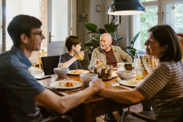 Grandfather and grandson having juice while sitting with...