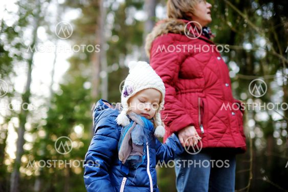 Little girl and her grandmother taking a walk in a forest