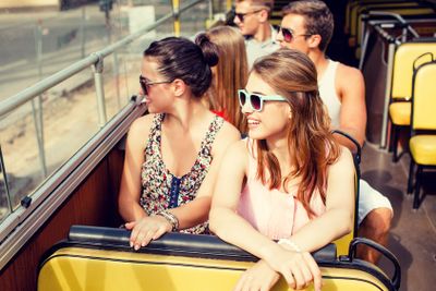 group of smiling friends traveling by tour bus