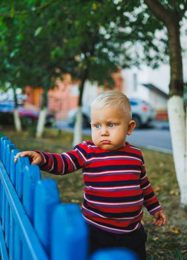 A fair-haired one-year-old boy in jeans and sneakers...