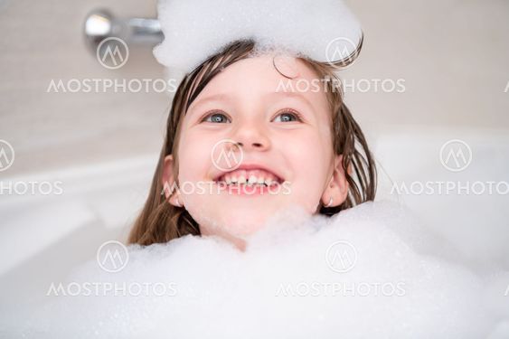 little girl in bath playing with foam
