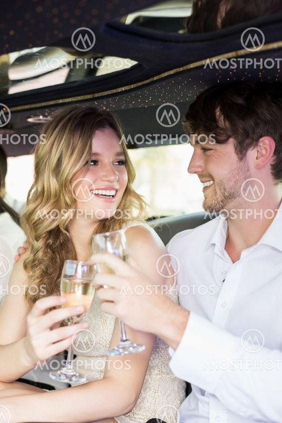 Well dressed couple drinking champagne in a limousine