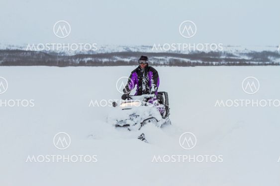 White man driving snowmobile