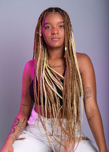 Brunette model with braids in her hair, wearing white...