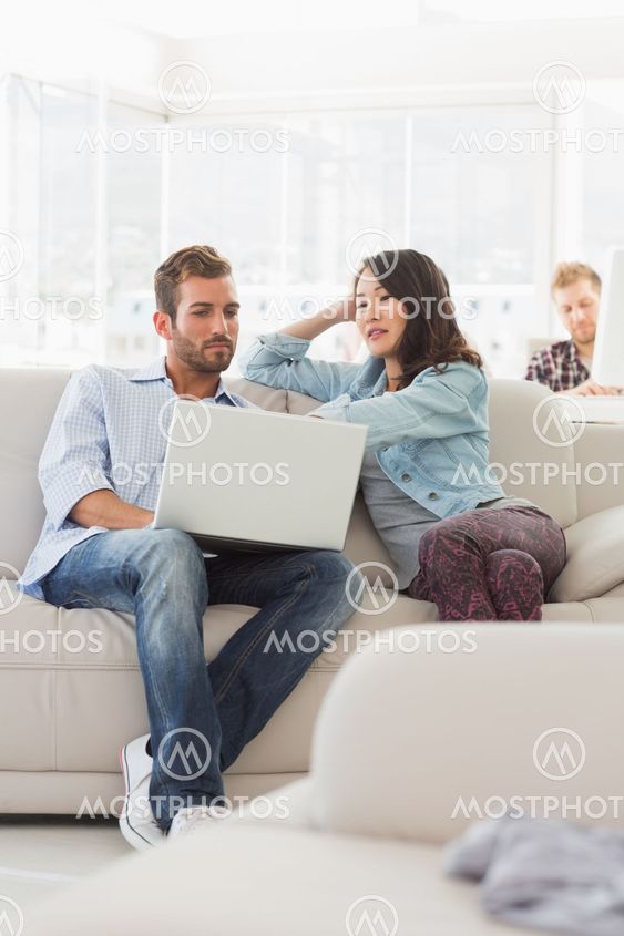 Focused designers working together on laptop on the couch