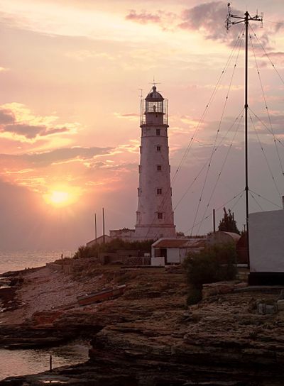 Lighthouse at sea coastline. Sunset on beach. Tined toned...