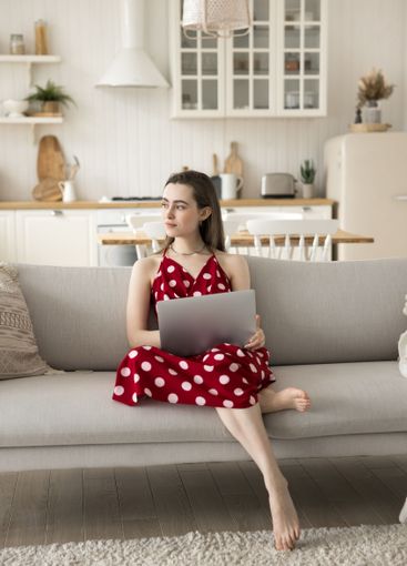 Pensive young girl sit on couch look aside from notebook