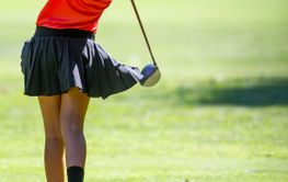 Girl golf player teeing-off with driver from tee-box