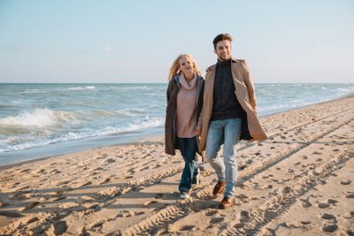 couple walking on seashore in autumn