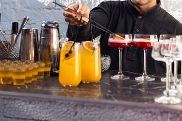 Bartender is preparing cocktails at bar. Man is mixing...