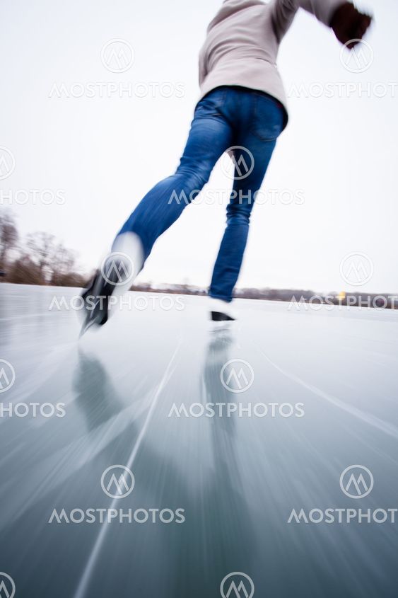 Young woman ice skating outdoors on a pond on a freezing winter day