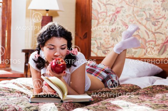 Woman in schoolgirl dress chews apple