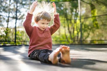 Little boy jumping on a trampoline in a backyard on warm...