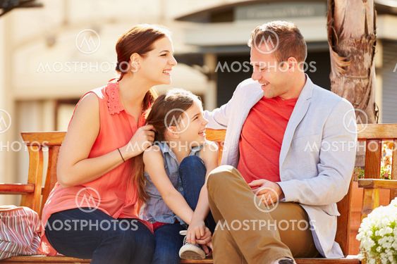 Young Family Sitting On Seat In Mall Together