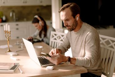 Businessman using smart phone and laptop while working at...