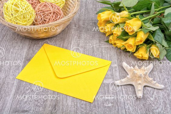 Envelope, starfish and roses on a wooden background