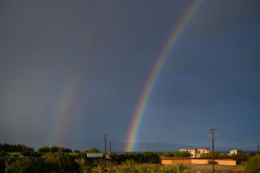 A vibrant rainbow arches over a serene landscape after a...