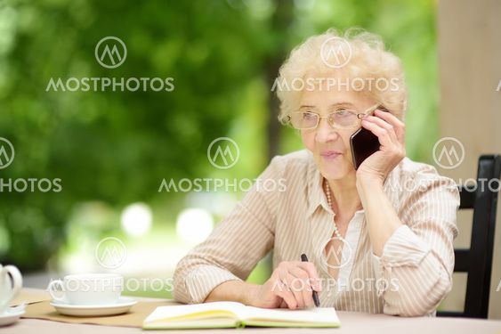 Beautiful senior lady with curly white hair working in...