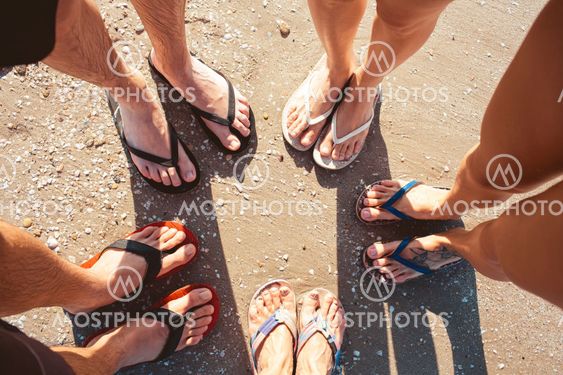 Five pare of legs on the sand of the beach