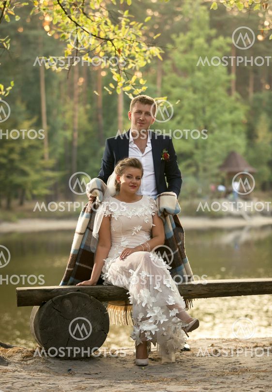 Toned photo of groom hugging bride sitting on bench at...