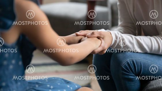 Close up caring mother holding little daughter hands,...