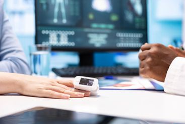 Physician using an oximeter on patient to measure oxygen...