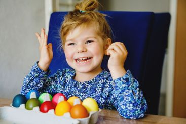 Excited little toddler girl coloring eggs for Easter....