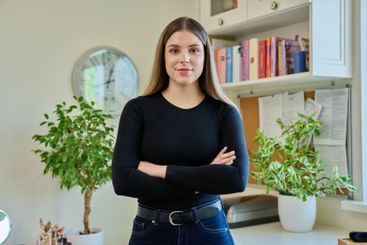 Confident young woman with crossed arms in home interior