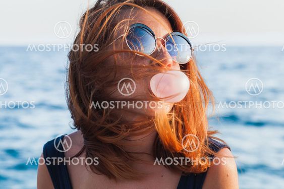 Young woman blowing bubble gum by the sea