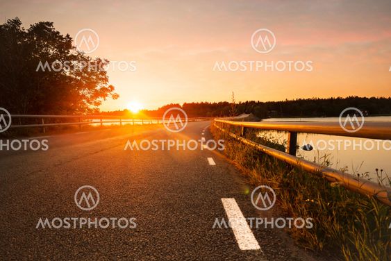Road and bridge with white border signs during a sunset,...