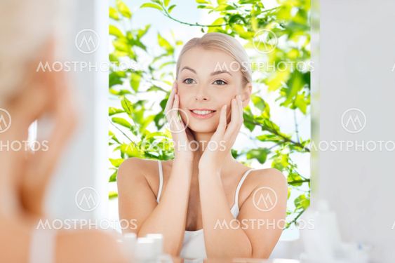happy young woman looking to mirror at bathroom