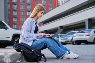 Young female college student using laptop computer outdoor