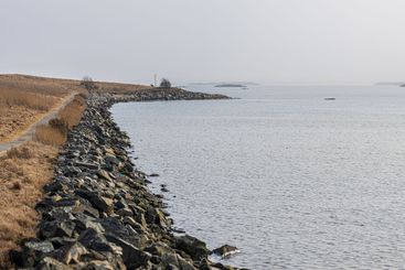 coastal pathway leading along rocky shoreline under an...