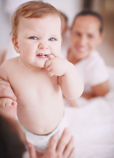 Baby, parents and teething with hands in home, love and...