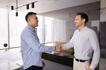 Happy male multiethnic business partners shaking hands...