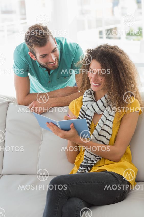 Smiling woman on the couch showing her co worker her notebook