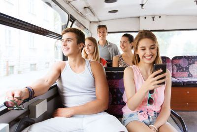 happy teenage friends traveling by bus