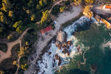 rocky cove with fishermen's huts next to a forest