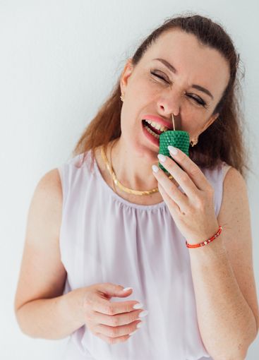 Beautiful brunette woman holding a green candle in her...