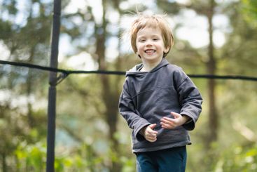 Little boy jumping on a trampoline in a backyard on warm...
