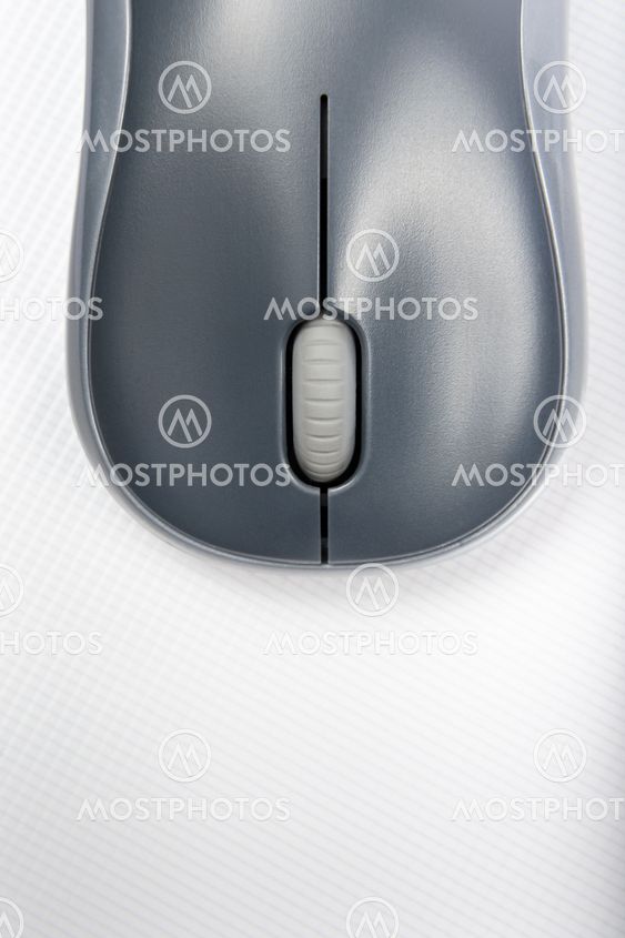 A wireless mouse positioned vertically on the cover of a laptop